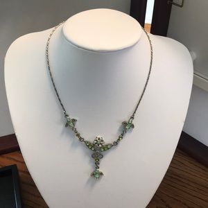 Silver colored necklace with green tone jewels.
